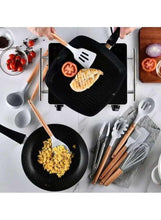 Silicone cooking utensils with wooden handles beside a skillet and chopping board