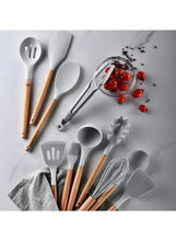 Kitchen utensils set with grey silicone heads and wooden handles arranged on a mat