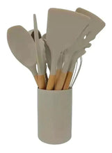 Beige silicone utensil set with wooden-handled spatulas and spoons in cup holder