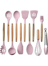 Assorted pink silicone cooking utensils with wooden handles, including spatula and whisk.