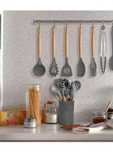 Silicone cooking utensil set with wooden handles, hanging on a wall rack