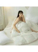 White winter duvet comforter wrapped around a person sitting on a bed