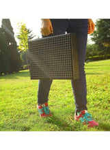 Portable charcoal BBQ grill, black wire grate top, being carried outdoors