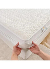 White quilted mattress topper edge with elastic underside, held by hands