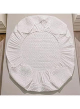 White quilted mattress topper, folded on display with patterned surface