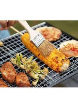 Charcoal grill grate with grilled fish and vegetables, with a brush applying sauce