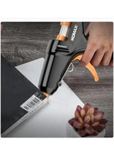 Mini hot glue gun applying glue on white card with flower piece