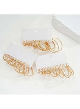 Gold-tone hoop and cuff earrings set with several hoop rings on display cards