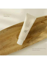 Moisturizing face sunscreen tube on a wooden surface, angled view.
