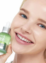 Green Anua 10+ serum bottle held near a smiling face with dropper