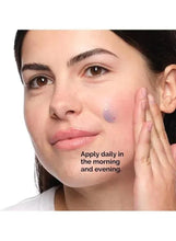 Woman applying blue gel serum to cheek with fingers