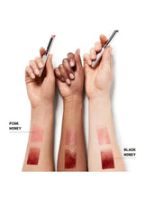 Hands holding lipstick with multiple lip swatches on fingertips and palms