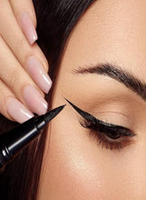 Hand applying deep black felt-tip eyeliner with a sharp wing on the eye