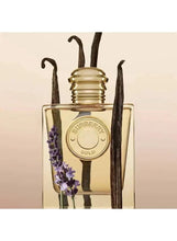 Gold-toned eau de parfum bottle with dark stems and lavender sprigs