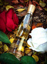Gold-capped eau de parfum bottle with pale yellow liquid among leaves and flowers
