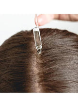 Hair serum dropper applying to scalp, metal tip above hair part