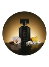 Black perfume bottle with floral and fruit accents in a gold circular frame