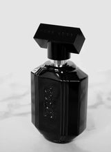 Black glass perfume bottle with metallic spray nozzle and faceted sides
