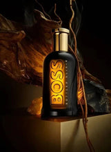 Men’s fragrance bottle with gold cap, black glass and glowing gold Boss Bottled lettering