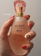 Rasasi Secret perfume bottle held in hand, pink cap and gold spray nozzle