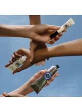 Hands holding small L'OCCITANE hand cream tubes