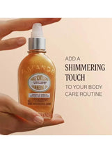 Almond shimmering body oil bottle with pump, amber-gold liquid