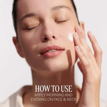 Woman applying face cream to her cheek with closed eyes.