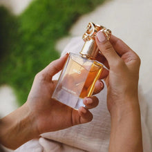 Person holding amber eau de parfum bottle with gold cap and 'WAJD' label