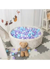 Mixed-color baby chew pool balls and star pieces spilling around a white basin
