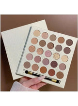 Cream eyeshadow palette with 25 pans and mirror, brush near the lower edge