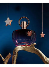 Dark perfume bottle with gold-toned emblem and rose-gold ring top