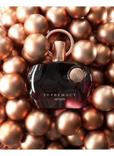 Perfume bottle with rose-gold ring and dark purple base, on bronze spheres