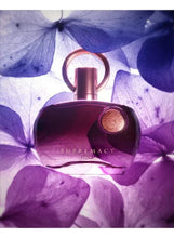 Purple perfume bottle with rose-gold cap and ring, on purple flower petals