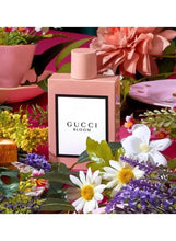 Gucci Bloom perfume bottle in pink with Gucci Bloom label, surrounded by flowers