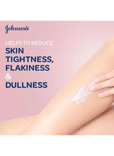 Hand spreading white body cream on an arm