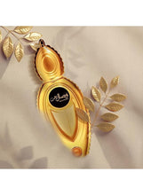 Gold perfume bottle with oval frame and 'Wisal Dhahab' label, tilted view