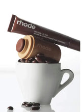 Lip tint duo with brown tube and beige balm pot beside white mug