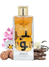 Amber eau de parfum bottle with gold cap amid flowers and wood pieces