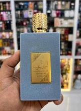 Blue perfume box with gold label, hand holding