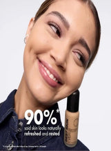 Woman smiling while holding a liquid foundation bottle with black cap
