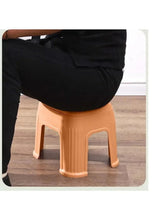 Orange plastic shoe stool under a seated person, showing top and legs