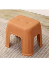 Orange plastic shoe stool with domed seat and side handhold openings
