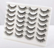 Wispy false eyelashes set with several cat-eye style pairs on a white tray