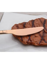 Rose gold stainless steel knife slicing steak on a plate
