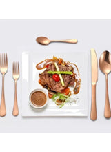Rose gold stainless steel spoon, fork, and knife beside plated steak and sauce
