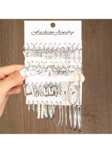 Silver hoop and charm earring set on jewelry cards, assorted silver-tone hoop and charm styles.