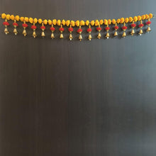 Long pom-pom door hanging with yellow beads and rows of red tassel bells