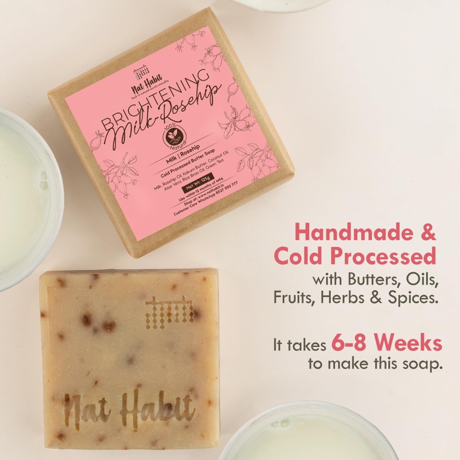Square beige soap bar with speckled flecks, near pink branded box