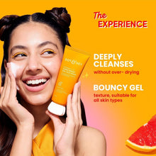Dot & Key vitamin C+E gel face wash tube held near a smiling woman’s cheek