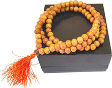 Cedar wood prayer mala with round beads and orange tassel, coiled on display box